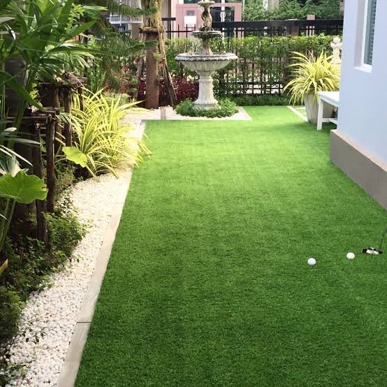 Artificial grass installation with white stepping stones showing professional placement and landscape design