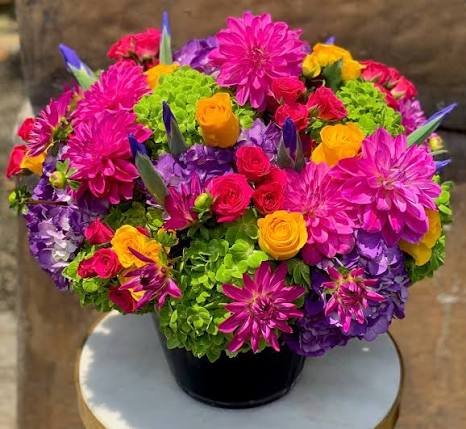 Colorful artificial gerbera daisy arrangement in white planter bowl with red orange pink and yellow blooms for outdoor event decor rental Saudi Arabia