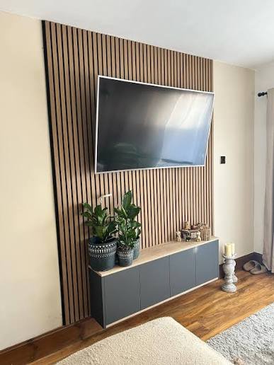Full width luxury media wall with fluted wood panels backlit niches and floating cabinetry in villa living room Riyadh