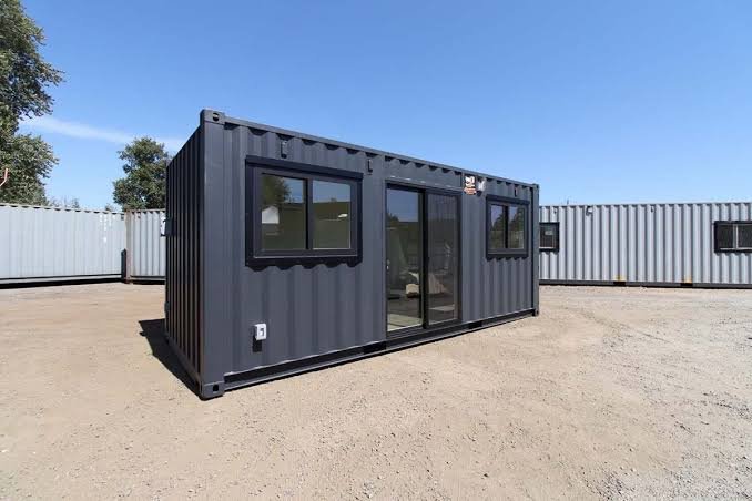 Modern black portable container with large windows and wooden deck entry creating professional office space