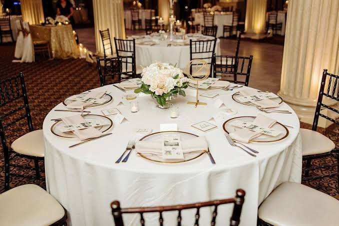 Elegant wedding reception with round tables, white linens and elaborate floral centerpieces